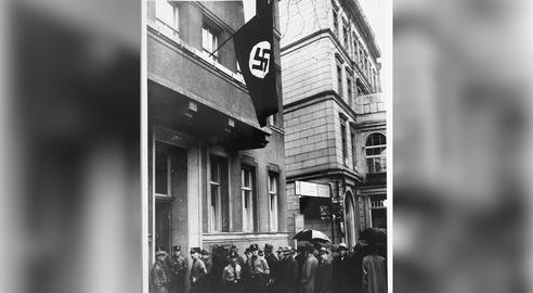 وکلای یهودی برای دریافت اجازه کار و حضور در دادگاه‌های برلین صف بسته‌اند. «اصل آریایی» مندرج در مقررات جدید (مجموعه قوانینی که در ماه آوریل سال ۱۹۳۳ و به‌ منظور پاکسازی یهودیان از حوزه‌های مختلف دولتی و اجتماعی وضع شدند) تنها به ۳۵ تن حق حضور در دادگاه را می‌داد.