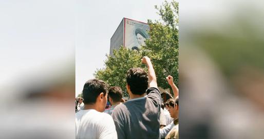 One of Mehgameh Parvaneh's famous photos shows a group of students with clenched fists chanting slogans on Enghelab Street in Tehran, right beneath a street painting of Ruhollah Khomeini and Ali Khamenei