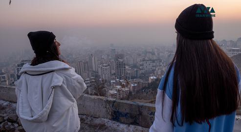 جوانان در بام تهران به شهر در آلودگی هوا نگاه می‌کنند. عکس از ایران‌وایر