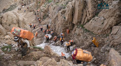 کولبران در حالی که وسایل مختلف را حمل می کنند در حال عبور از کوه‌های مرز ایران و عراق هستند.