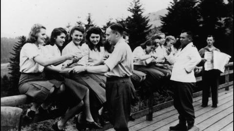 SS female auxiliaries relax on a fence railing eating blueberries in Solahütte, an SS resort in occupied Poland near the Auschwitz concentration camp. Image Source: United States Holocaust Memorial Museum