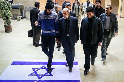Kayhan's editor-in-chief, the Supreme Leader appointee Hossein Shariatmadari, walks over the Israeli flag at a meeting