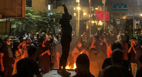 در جریان اعتراضات سراسری ۱۴۰۱ دختری بدون حجاب اجباری در کنار آتشی که معترضین روشن کرده‌اند، شعار می‌دهد. تهران