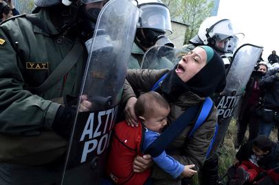 A refugee mother with her child confronts the Greek riot police outside Diavata refugee camp