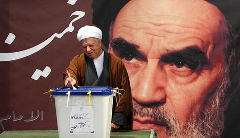 Rafsanjani, who was president of Iran from 1989 to 1997, votes in front of a portrait of Khomeini