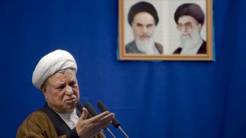 Rafsanjani speaks beneath portraits of Khomeini and Ali Khamenei, the man he helped to become supreme leader