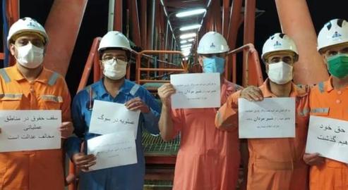 Striking Iranian oil and gas workers have downed tools and held up banners proclaiming: “We will not forgo our rights”