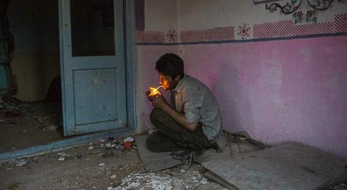 A man addicted to drugs smokes at the abandoned Vakili Palace in Neyshabur