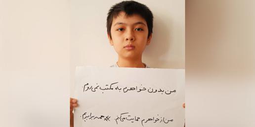 تصویری از پسری که روی پلاکارد خود نوشته است: «من بدون خواهرم به مکتب نمی‌روم.»
