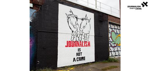 A striking mural of a pair of hands in handcuffs with the words “Journalism Is Not A Crime” is hard to miss if you stroll through the Astoria neighborhood in Queens, New York.