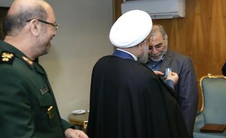 حسن روحانی در حال اهدا مدال به محسن فخری زاده. سرتیپ پاسدار حسین دهقان وزیر وقت دفاع ایران هم حضور دارد.