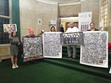 Activists hold up photos of the 1988 and November 2019 victims side by side at Church House, Westminster