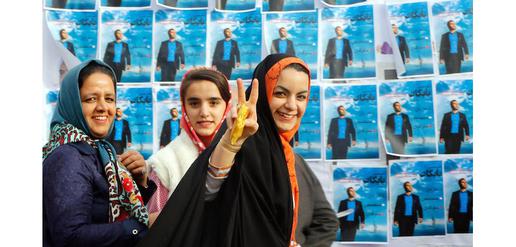 Women walk past electoral posters for the upcoming elections 