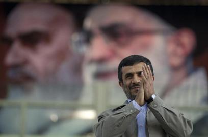 Ahmadinejad under portraits of Khamenei and Khomeini