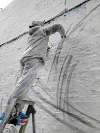 Greek muralist Argiris Ser works on his mural on Holywell Lane, Shoreditch, London