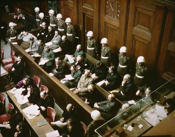 متهمان در دادگاه  نمایی از جایگاه متهمان به جنایات جنگی در دادگاه نظامی بین‌المللی در نورنبرگ. نوامبر ۱۹۴۵.  منبع: اداره آرشیو و سوابق ملی، کالج پارک، مریلند.